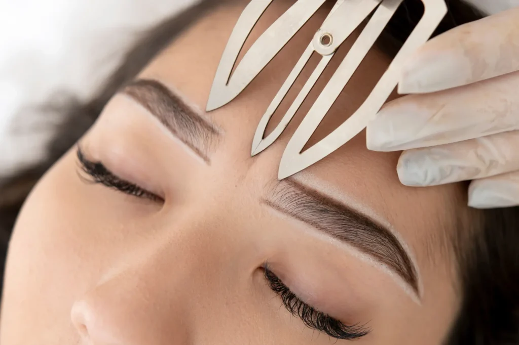 Medición de diseño de cejas con regla de precisión en los tratamientos de cejas en Ari Martínez Beauty